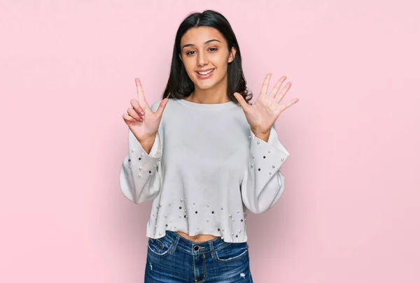 Młoda Latynoska Dziewczyna Luźnych Ubraniach Pokazując Wskazując Palcami Numer Siedem — Zdjęcie stockowe