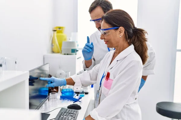 在实验室工作的中年男人和女人穿着科学家制服 — 图库照片