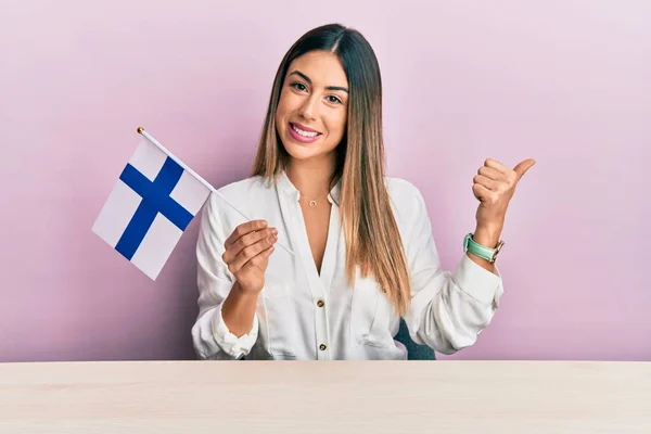Young Hispanic Woman Holding Finland Flag Sitting Table Smiling Happy — Stock fotografie