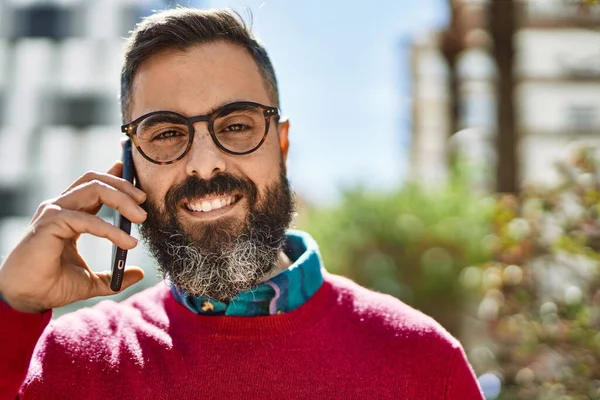 Genç İspanyol yönetici gülümsüyor. Şehirdeki akıllı telefondan konuşuyor..