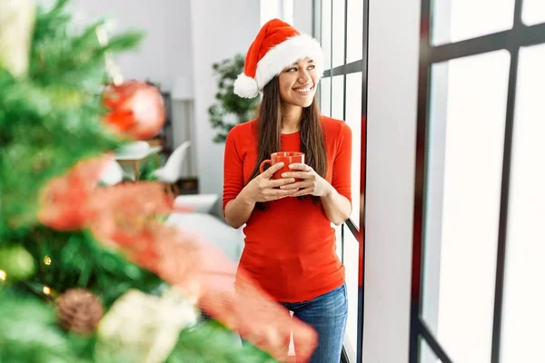 Genç Latin Kadın Evde Noel Ağacının Yanında Kahve Içiyor — Stok fotoğraf