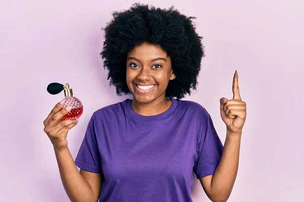 Young African American Woman Holding Perfume Smiling Idea Question Pointing — Stockfoto