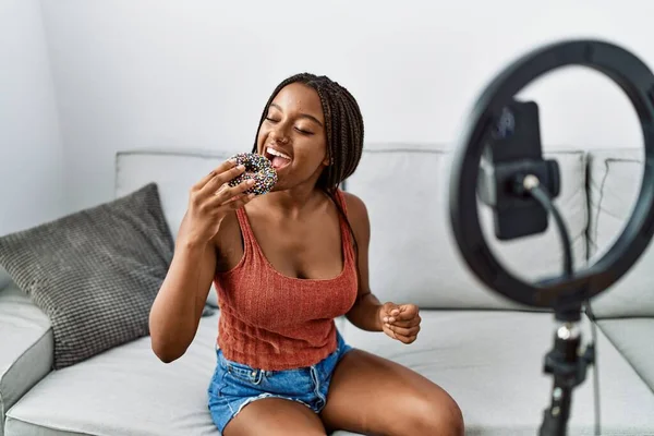 Νεαρή Αφροαμερικανή Γυναίκα Τρώει Ντόνατ Εγγραφή Βίντεο Φροντιστήριο Στο Σπίτι — Φωτογραφία Αρχείου