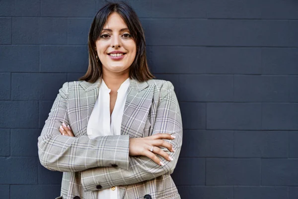 Genç İspanyol iş kadını şehirde çapraz hareketlerle mutlu gülümsüyor..