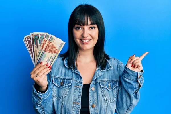 Genç İspanyol kadın elinde Mısır banknotları tutarken mutlu bir şekilde gülümsüyor. 