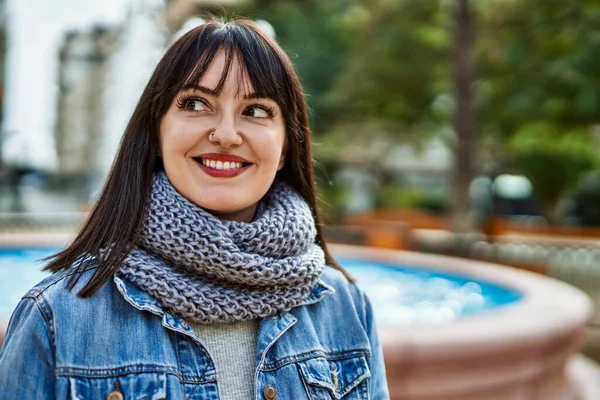 Genç esmer kadın parkta mutlu gülümsüyor.