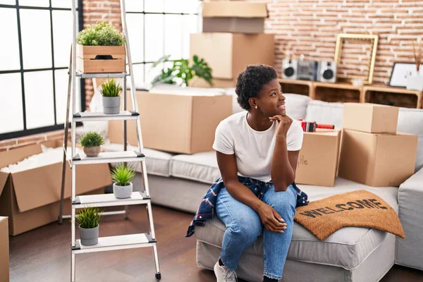 Afro-Amerikalı kadın yeni evindeki koltukta kendinden emin bir şekilde oturuyor.
