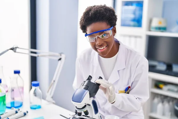 实验室显微镜下身穿科学家制服的非洲裔美国妇女 — 图库照片
