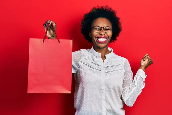Joven Mujer Afroamericana Sosteniendo Bolsas Compras Gritando Orgulloso Celebrando Victoria —  Fotos de Stock