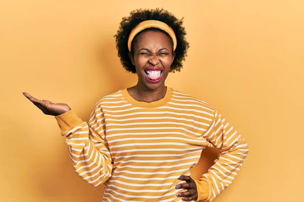 Genç Afro-Amerikalı kadın avuçlarını açmış, elinde bir şey tutarken mutlu bir ifadeyle dilini dışarı çıkartıyor.. 