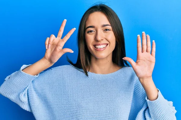 Gündelik kıyafetler giyen genç İspanyol kız gülümseyerek kendinden emin ve mutlu bir şekilde sekiz numarayı gösteriyor ve işaret ediyor.. 