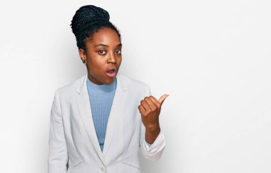 İş kıyafetleri giymiş genç Afro-Amerikan bir kadın elleri yana dönük, ağzı açık, şaşkın bir ifadeyle şaşırdı.. 