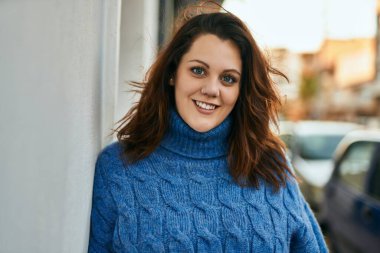 Genç İrlandalı artı cüsseli kız gülümseyerek şehirde mutlu mesut duruyor..