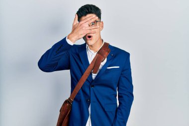 İş kıyafetleri giyen genç İspanyol adam şok içinde yüzünü ve gözlerini kapayarak utangaç bir ifadeyle parmaklarından bakıyor.. 