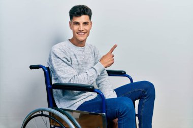 Tekerlekli sandalyede oturan, yüzünde kocaman bir gülümseme olan, eli kameraya bakan genç İspanyol bir adam.. 