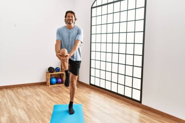 Orta yaşlı, beyaz, gülümseyen, spor merkezinde kendine güvenen bir adam.