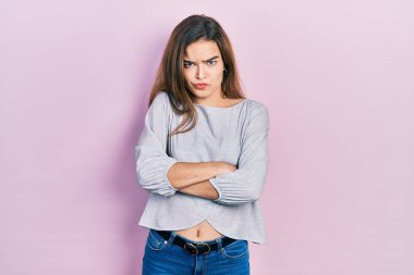 Gündelik kıyafetler giyen, kuşkucu ve gergin genç beyaz bir kız. Yüzünde çapraz kollarla onaylamayan bir ifade var. negatif kişi. 