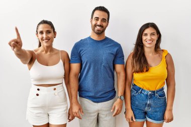 İzole edilmiş arka planda duran bir grup İspanyol genç bir numaralı parmağı gösterip işaret ederken kendinden emin ve mutlu bir şekilde gülümsüyor.. 