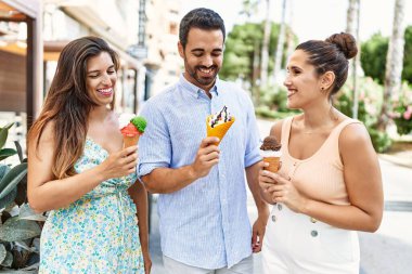 Üç İspanyol arkadaş gülerek şehirde dondurma yiyor..