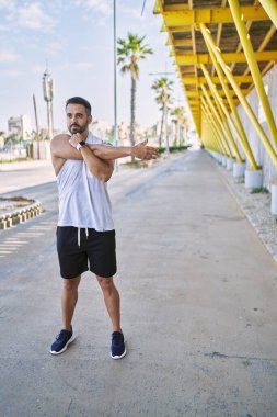 Güneşli bir günde dışarıda çalıştıktan sonra kollarını esneten İspanyol bir adam.