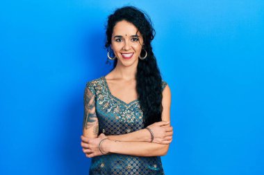 Bindi ve geleneksel kurta elbisesi giyen genç bir kadın kollarını kavuşturup kameraya bakarken gülümsüyor. pozitif kişi. 