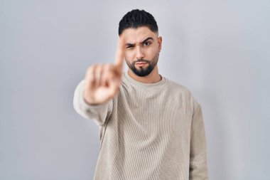 Soyutlanmış arka planda duran yakışıklı genç adam parmağını kaldırmış ve kızgın bir ifadeyle işaret ediyor, hiçbir hareket göstermiyor. 