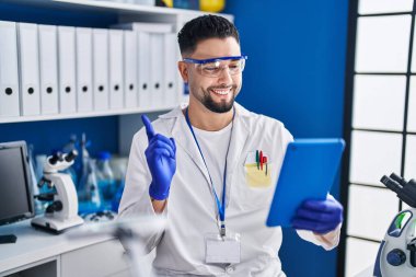 Laboratuvarda çalışan genç yakışıklı adam internette aranıyor. Gülümsüyor, mutlu bir şekilde işaret ediyor. 