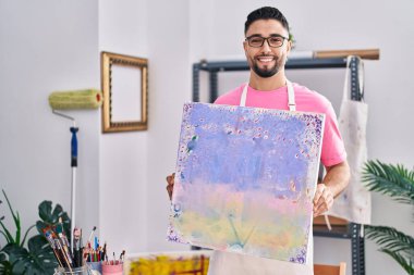 Genç Arap sanatçı gülümsüyor. Sanat stüdyosunda kendine güveni tam.