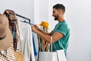 Genç Arap müşteri kıyafet mağazasında kendine güvenen bir alışveriş yapıyor.