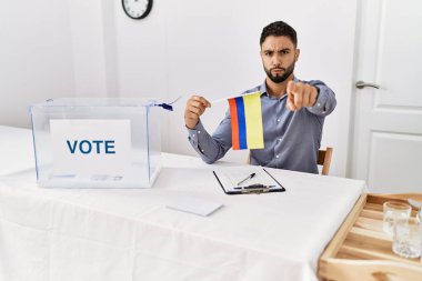 Siyasi seçim kampanyasında sakallı yakışıklı bir genç elinde kamerayı işaret eden bir Kolombiya bayrağı tutuyor ve kendine güveni tam bir jest yapıyorsun. 