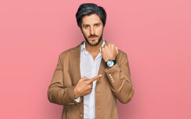 İş kıyafetleri giymiş genç bir İspanyol saati, sabırsızlığı ve rahat bir ifadeyle kameraya bakmayı işaret ediyor. 