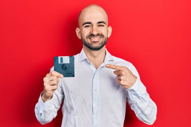 Disket tutan genç kel adam gülümsüyor mutlu bir şekilde eli ve parmağı ile işaret ediyor. 