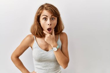 Güzel, beyaz bir kadın izole edilmiş arka planda duruyor. İnançsızlığa, şaşkınlığa ve elleri çenesinde olan şaşkınlık ifadesine hayran bakıyor. 