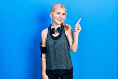 Güzel, beyaz saçlı, sarı saçlı spor giysili bir numaralı parmağını gösterip gösterirken kendine güvenen ve mutlu bir şekilde gülümseyen bir kadın.. 