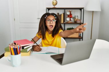 Genç Afrikalı Amerikalı ev ödevi yapıyor. Parmakla işaret ediyor. Şaşırmış, ağzı açık. 