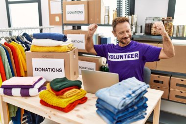 Orta yaşlı bir adam dizüstü bilgisayarla çalışırken gururla gülümseyen kol kaslarını gösteriyor. fitness konsepti. 