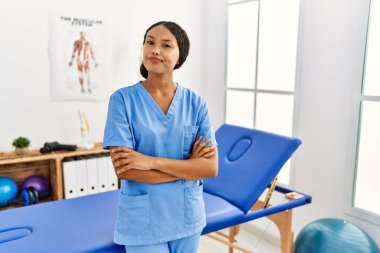Güzel İspanyol fizyoterapist kadın ağrı kesici kliniğinde gülümsüyor ve yan tarafa bakıyor.. 