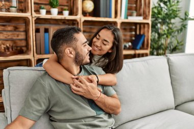 Kanepede oturan genç latin çift evde sarılıyorlar..