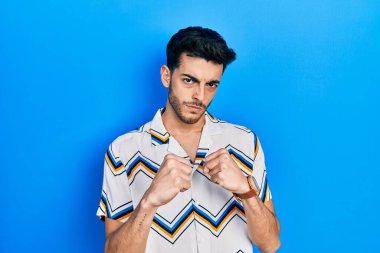 Latin asıllı genç adam gündelik giysiler giyiyor. Yumruk savunma hareketiyle dövüşmeye hazır. Kızgın ve üzgün yüz, sorundan korkuyor. 