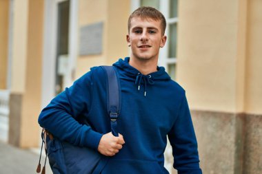 Üniversitede mutlu bir şekilde gülümseyen genç sarışın öğrenci..