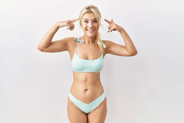 Young Caucasian Woman Wearing Bikini Isolated Background Smiling Pointing Head — стоковое фото