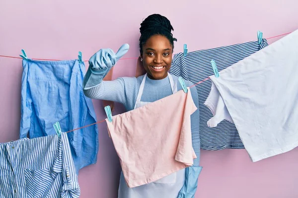 手で積極的なジェスチャーを行うことを承認し 布で編組髪洗濯服を持つアフリカ系アメリカ人女性 親指アップ笑顔と成功のために幸せ 勝者のジェスチャー — ストック写真