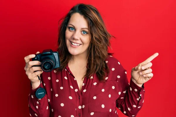 Jovem Caucasiana Segurando Câmera Reflexa Sorrindo Feliz Apontando Com Mão — Fotografia de Stock