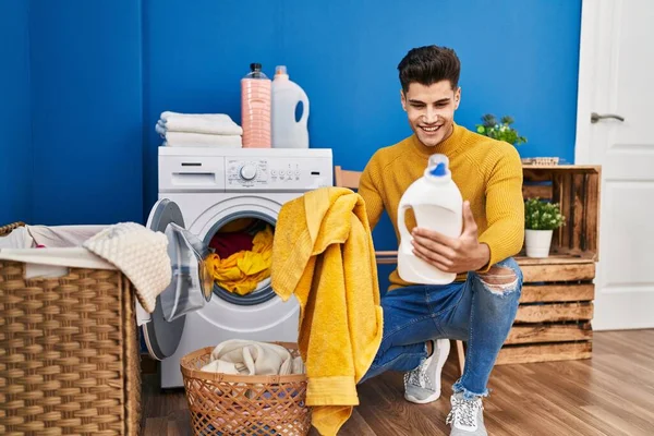 Jovem Hispânico Lavando Roupas Segurando Garrafa Detergente Lavanderia — Fotografia de Stock