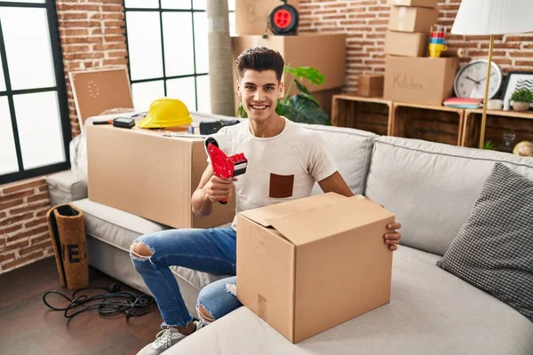 Jonge Spaanse Man Glimlachend Zelfverzekerd Verpakking Kartonnen Doos Nieuw Huis — Stockfoto