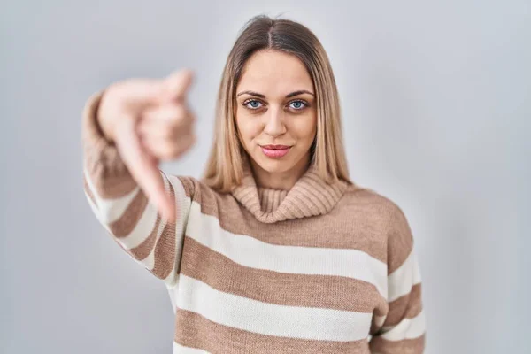 年轻的金发女人穿着高领毛衣 背景孤立 看起来不高兴 表示拒绝和负面的大拇指向下的手势 不好的表达方式 — 图库照片