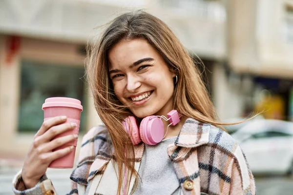 Νεαρή Ξανθιά Γυναίκα Που Φοράει Ακουστικά Κρατώντας Καφέ Στο Δρόμο — Φωτογραφία Αρχείου