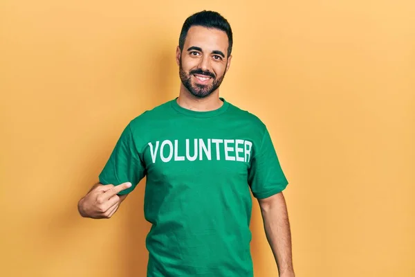 Handsome Hispanic Man Beard Wearing Volunteer Shirt Smiling Happy Pointing — 스톡 사진