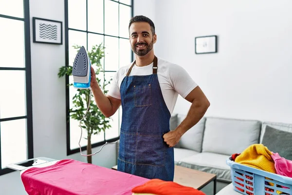 Ung Latinamerikansk Man Ler Säker Strykning Kläder Hemma — Stockfoto