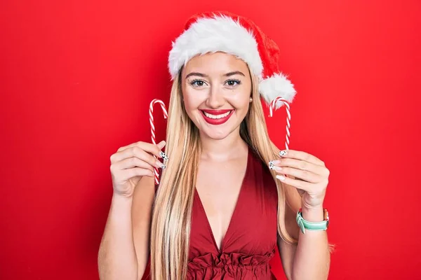 Νεαρό Ξανθό Κορίτσι Που Φοράει Χριστουγεννιάτικο Καπέλο Κρατώντας Καραμέλα Χαμογελώντας — Φωτογραφία Αρχείου